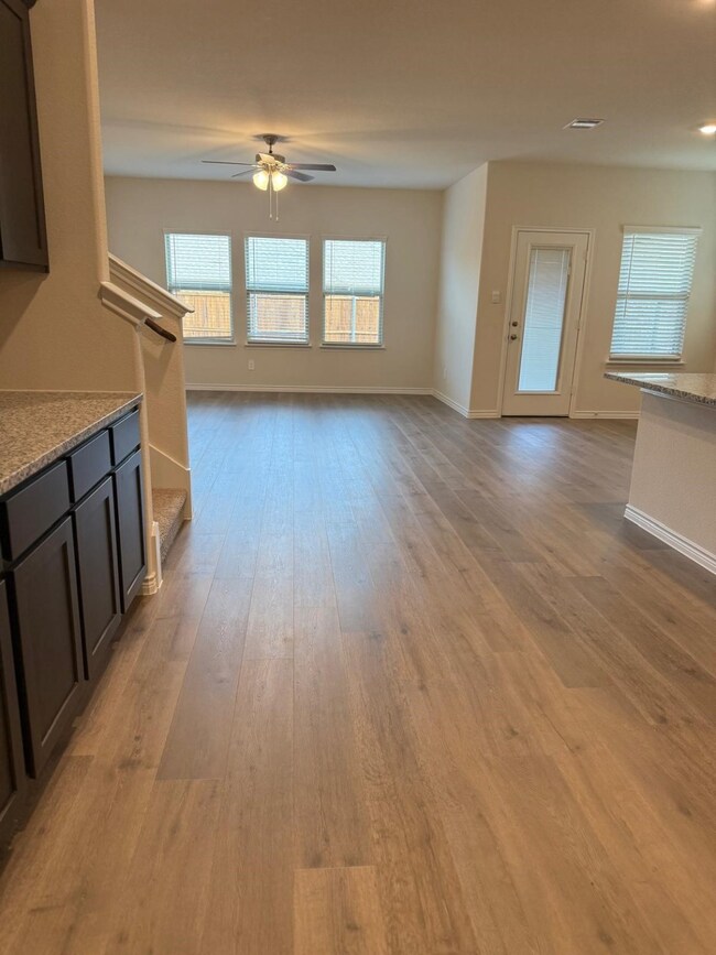Unfurnished living room featuring light wood-type flooring, stairs, and ceiling fan