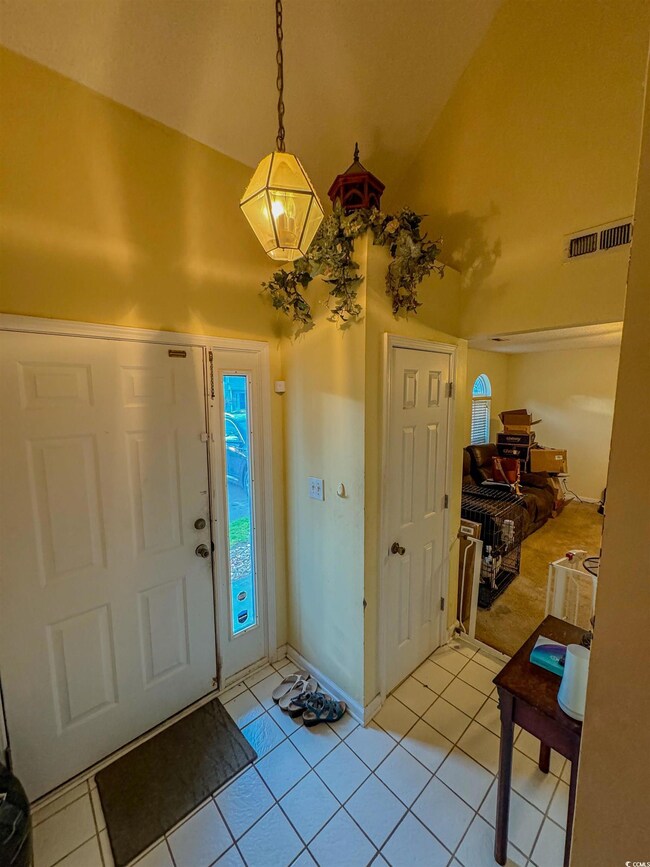 Tiled foyer featuring vaulted ceiling