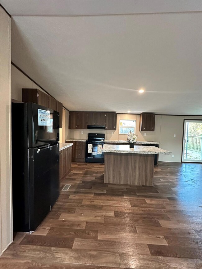 Kitchen featuring dark brown cabinets, dark hardwo