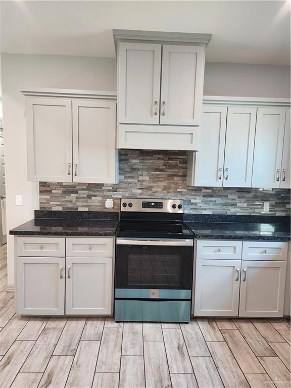 Kitchen featuring stainless steel range oven, extractor fan, light wood-type flooring, and backsplash