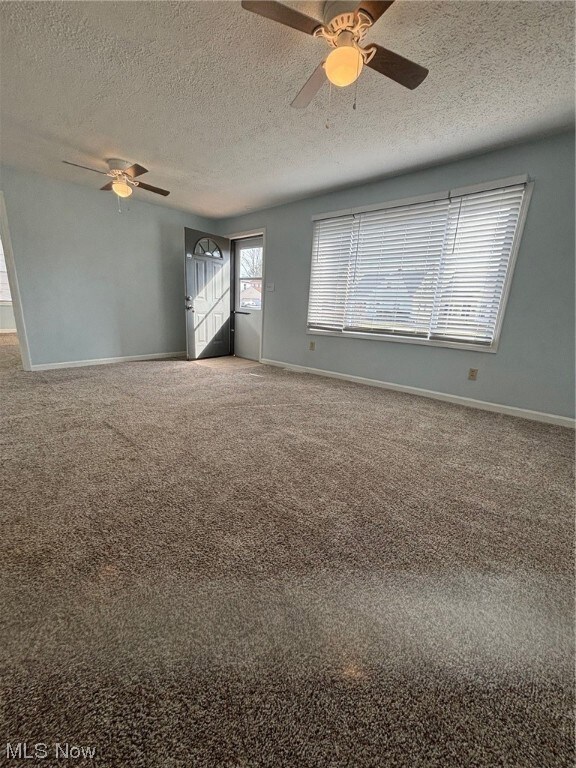 Carpeted spare room with ceiling fan and a textured ceiling