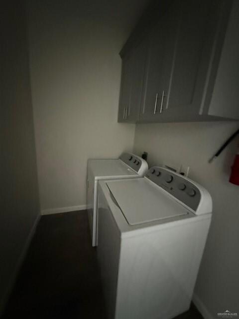 Laundry area featuring washing machine and dryer, cabinet space, and baseboards