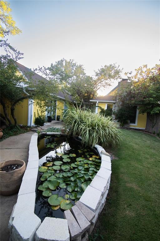 View of grassy yard with a small pond