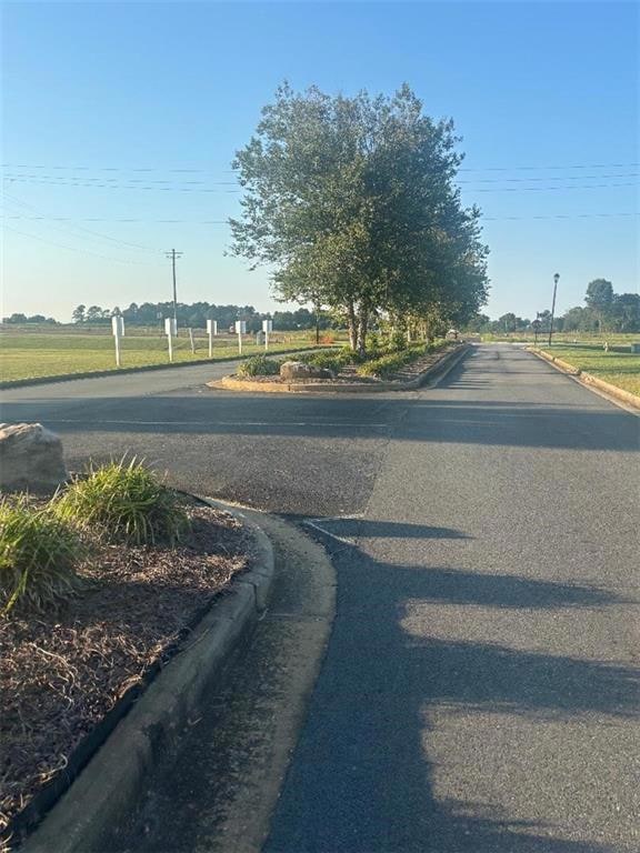 View of asphalt road featuring curbs and street lighting