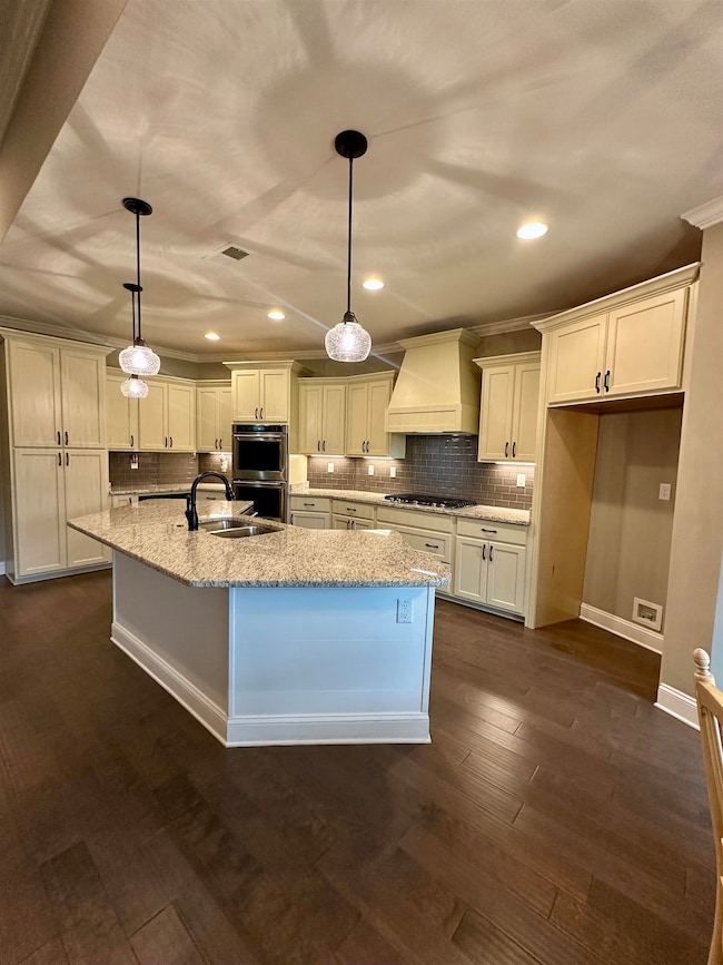 Kitchen with custom range hood, appliances with stainless steel finishes, tasteful backsplash, white cabinets, and recessed lighting
