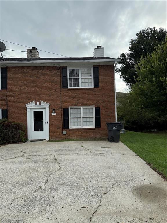View of front facade featuring a chimney and brick siding