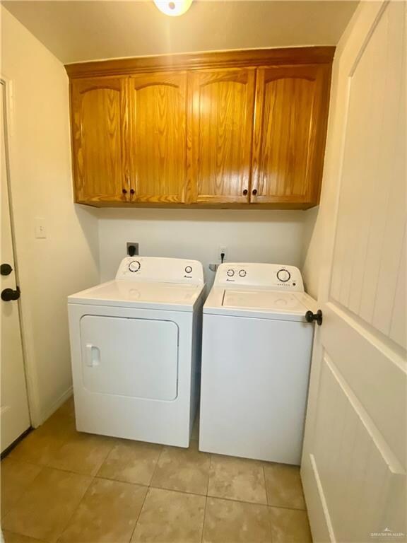 Laundry room featuring washing machine and dryer, light tile patterned floors, and cabinet space