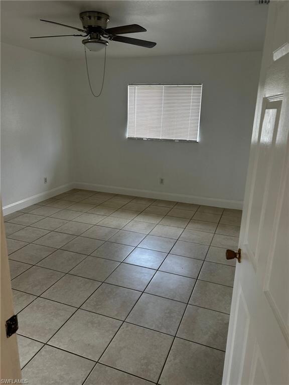 Unfurnished room featuring light tile patterned flooring, a ceiling fan, and baseboards