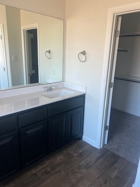 Bathroom featuring vanity, a spacious closet, and dark wood-type flooring