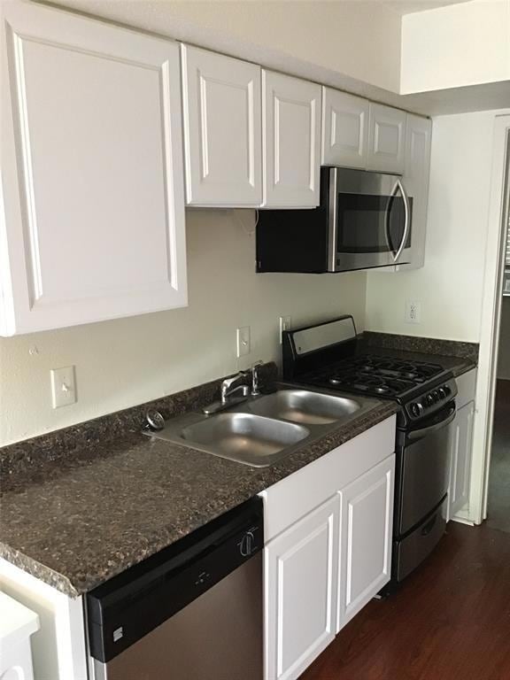 Kitchen with white cabinets, appliances with stai