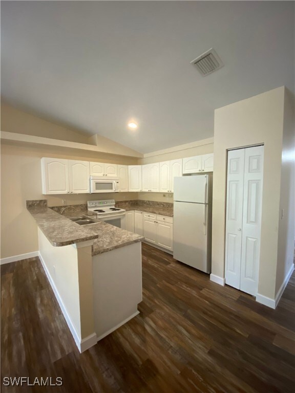 Kitchen with white appliances, a peninsula, white