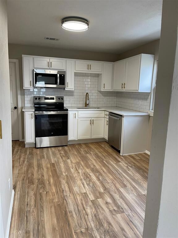Kitchen with white cabinets, appliances with stain