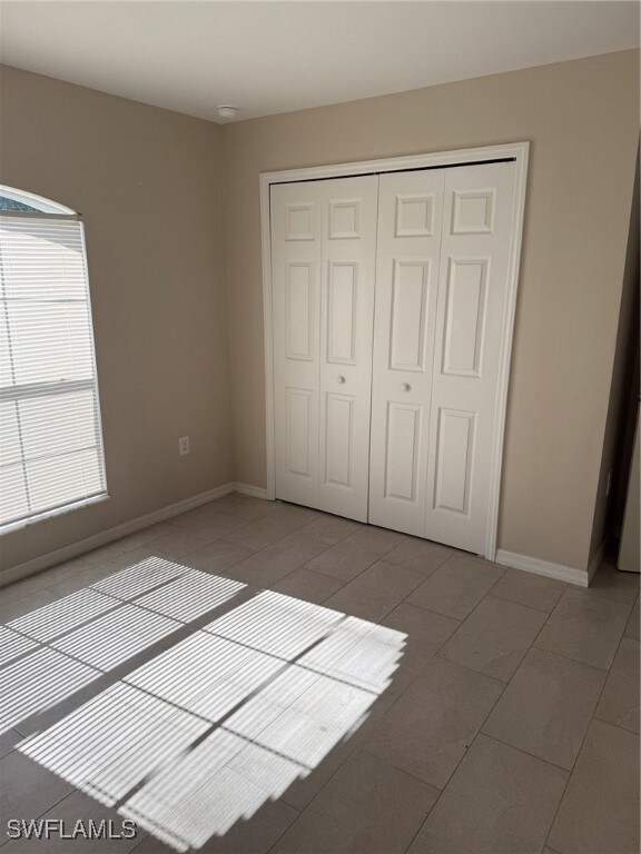 Unfurnished bedroom with a closet, light tile patt