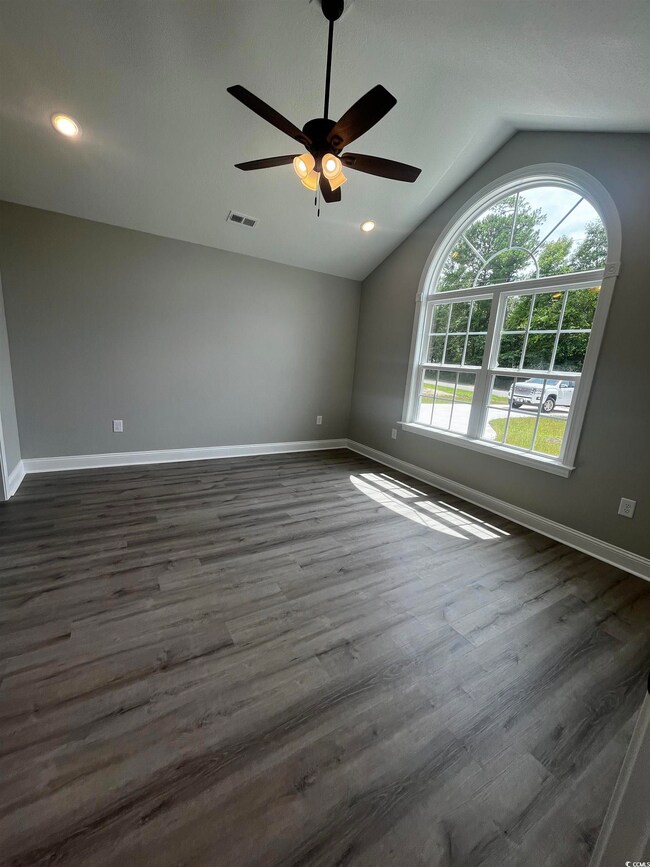 Spare room with lofted ceiling, ceiling fan, and d