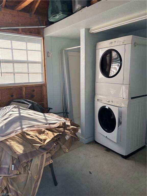 Laundry room featuring stacked washer / drying machine and concrete flooring