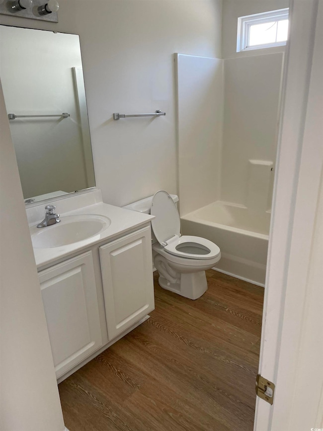 Bathroom featuring vanity, dark wood finished floors, and shower / bathtub combination