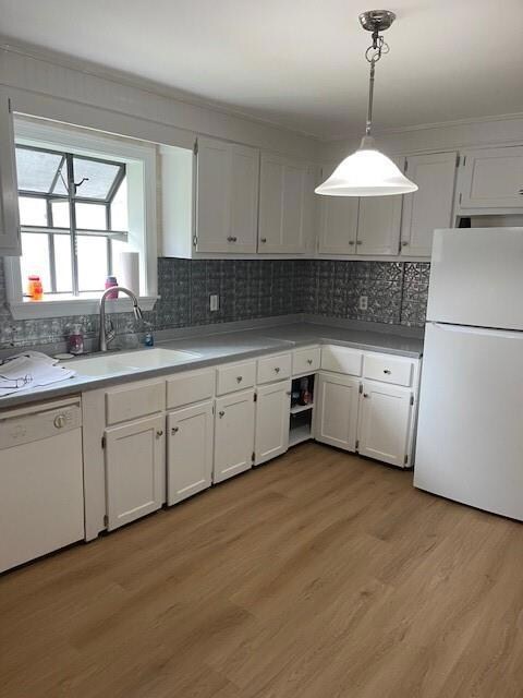 Kitchen with refrigerator, decorative backsplash, white cabinets, dishwasher, and hanging light fixtures