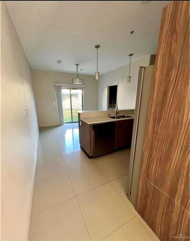 Kitchen with a sink, light tile patterned floors, light countertops, decorative light fixtures, and appliances with stainless steel finishes