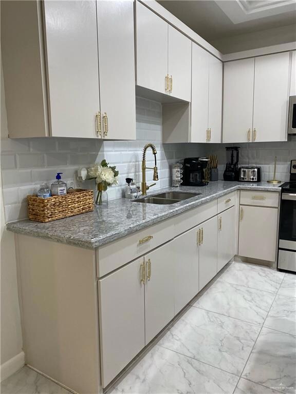 Kitchen with sink, tasteful backsplash, and white cabinetry