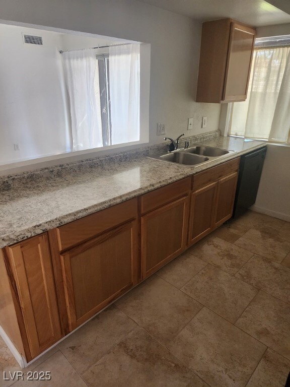 Kitchen featuring a sink, brown cabinetry, and lig