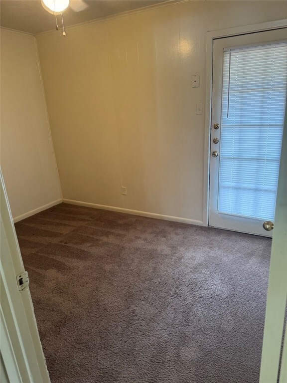 Empty room with dark colored carpet, baseboards, a