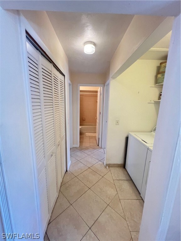 Hall featuring washer and dryer and light tile floors