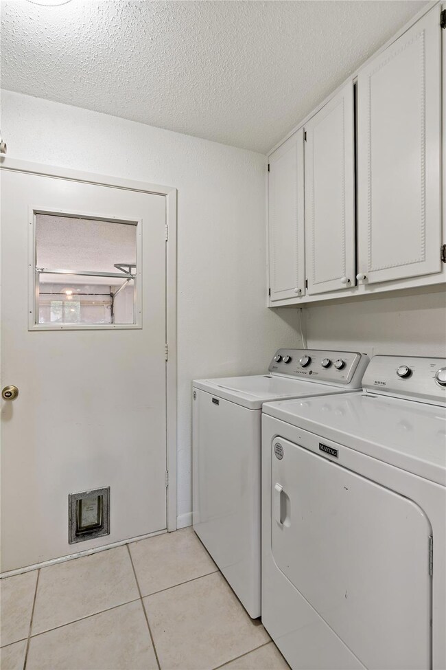 Laundry area with cabinets, a textured ceiling, li