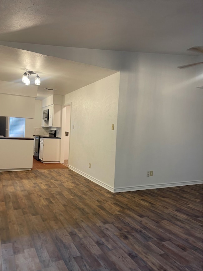 Unfurnished living room featuring dark wood finished floors and a ceiling fan