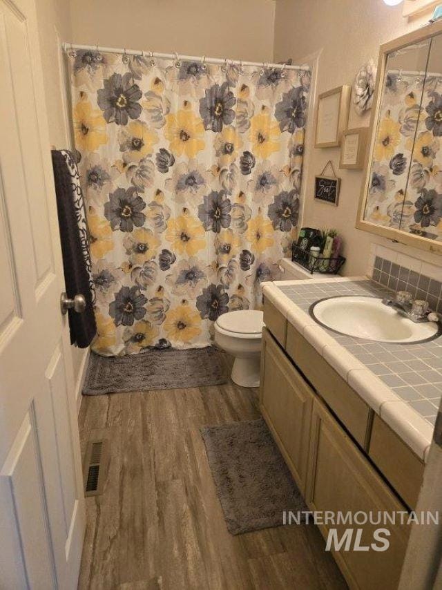 Bathroom with wood finished floors, vanity, and curtained shower