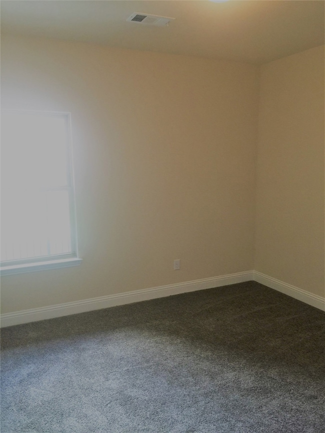 Empty room featuring dark colored carpet and baseboards