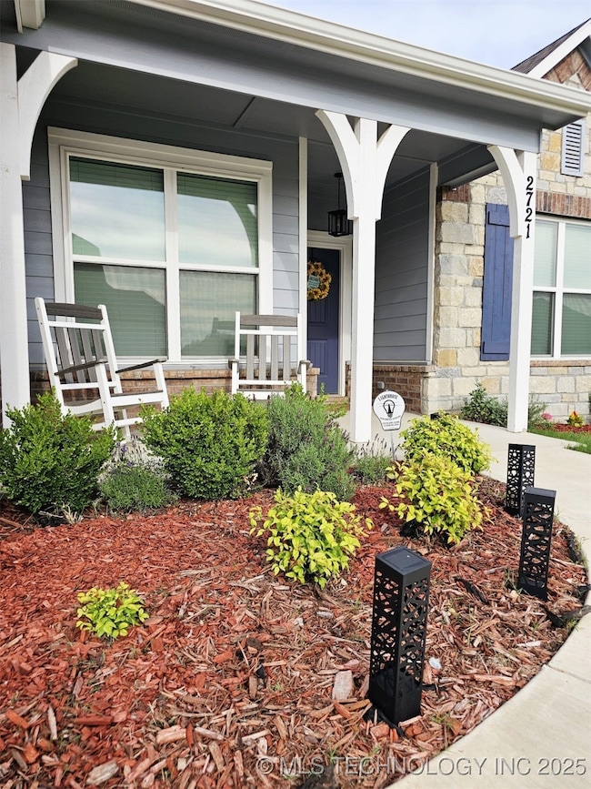 Doorway to property with covered porch and stone siding