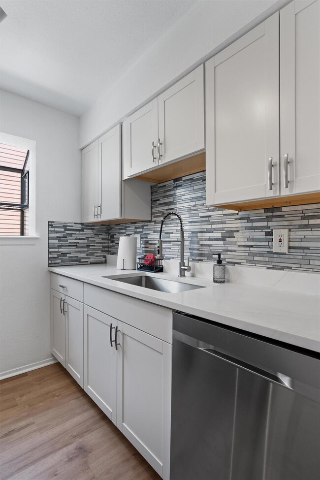 Kitchen featuring dishwasher, backsplash, light c
