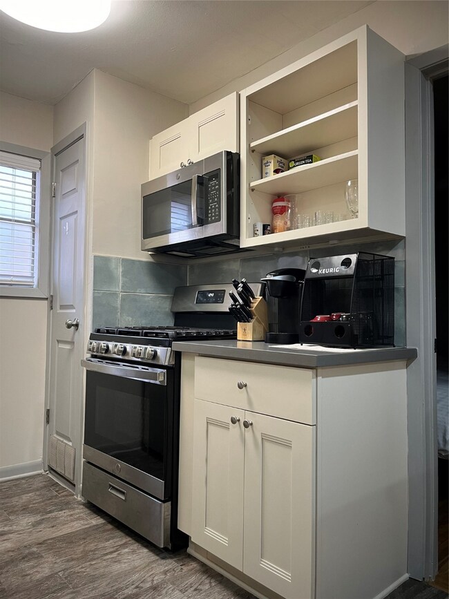 The kitchen features a gas stove/oven, microwave,