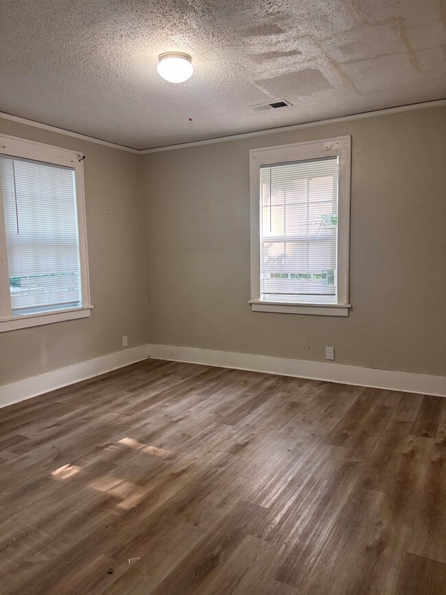 Empty room featuring dark wood-type flooring and a textured ceiling