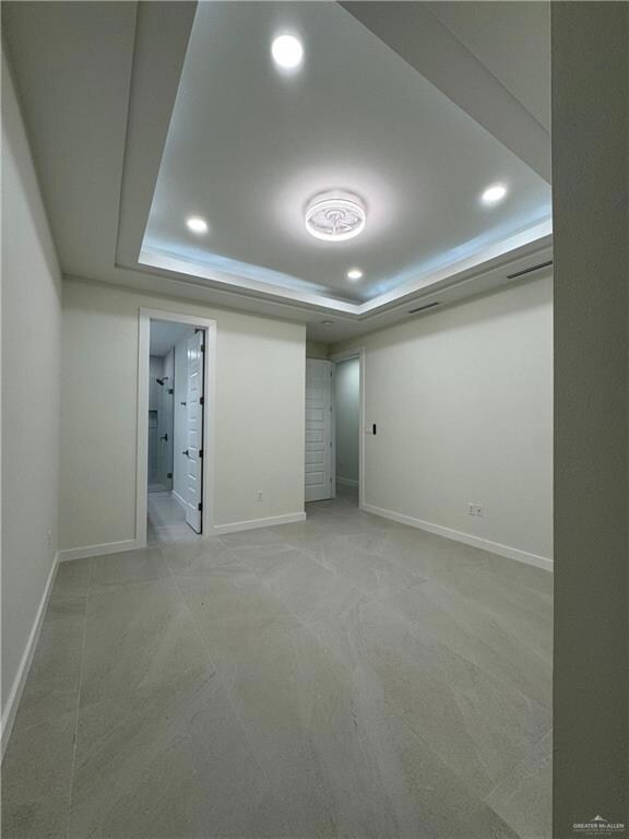 Unfurnished bedroom featuring light carpet, recessed lighting, and a raised ceiling