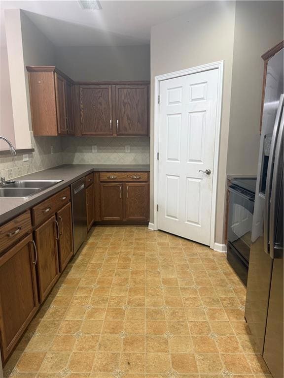 Kitchen with dark countertops, tasteful backsplash, stove, refrigerator, and dishwashing machine