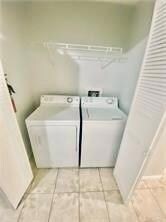 Washroom featuring washing machine and dryer and light tile patterned floors
