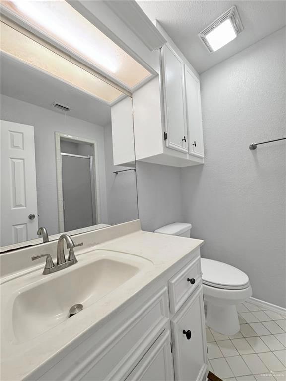 Bathroom with tile patterned flooring, vanity, a shower with shower door, and toilet