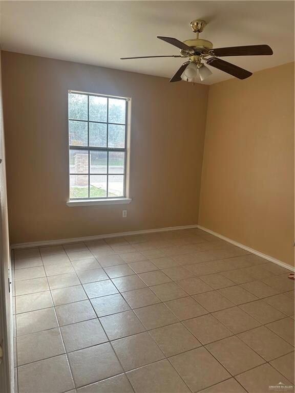 Spare room with light tile patterned floors, a ceiling fan, and baseboards