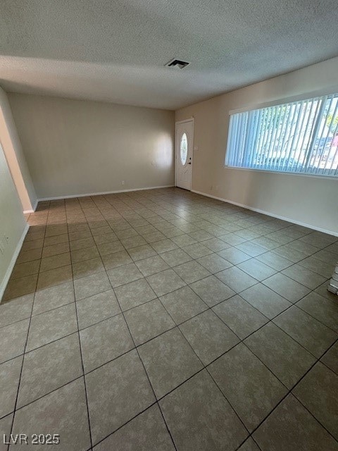 Unfurnished living room featuring a textured ceiling and light tile patterned flooring