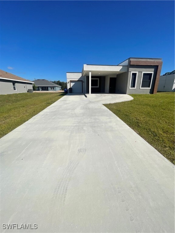 View of front of house with a front lawn and a car
