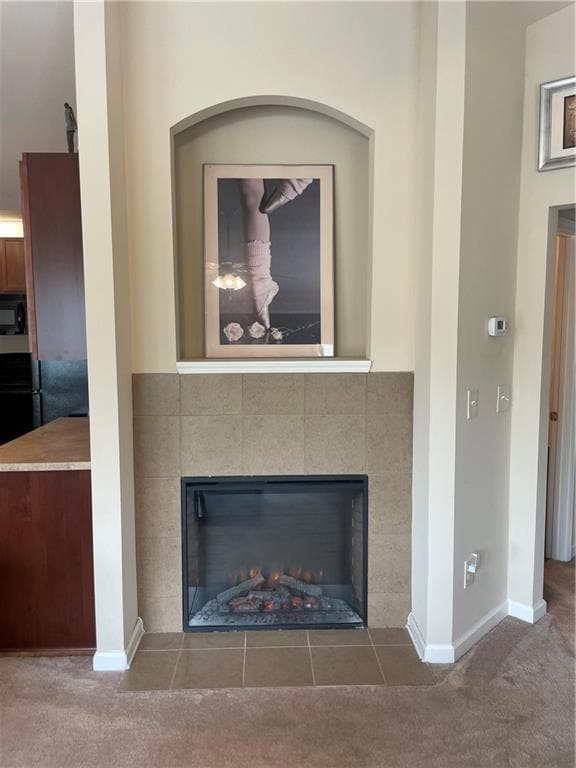 Detailed view of a tile fireplace, carpet floors, and baseboards