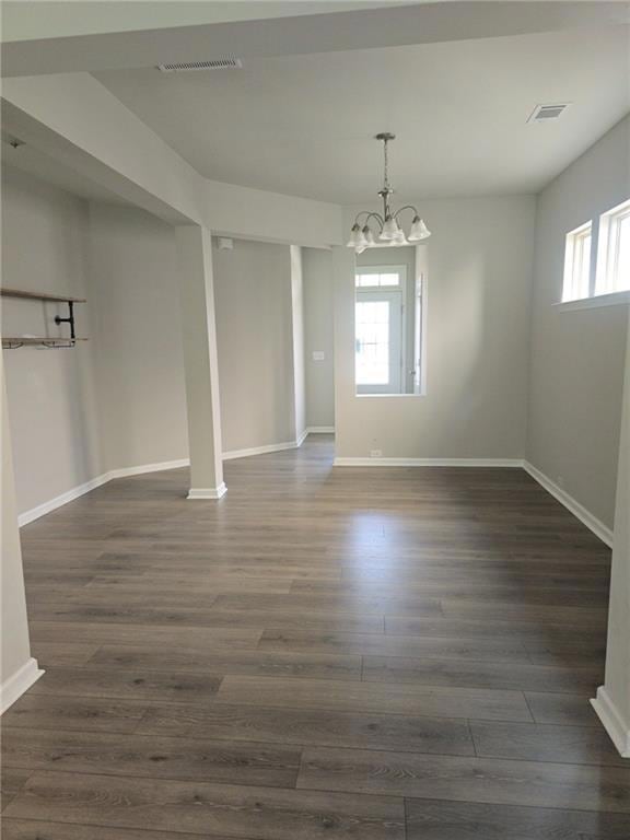 Unfurnished dining area featuring a chandelier and dark wood-type flooring