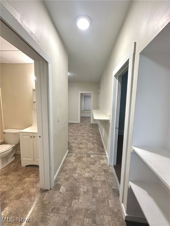 Corridor with baseboards and stone finish floors