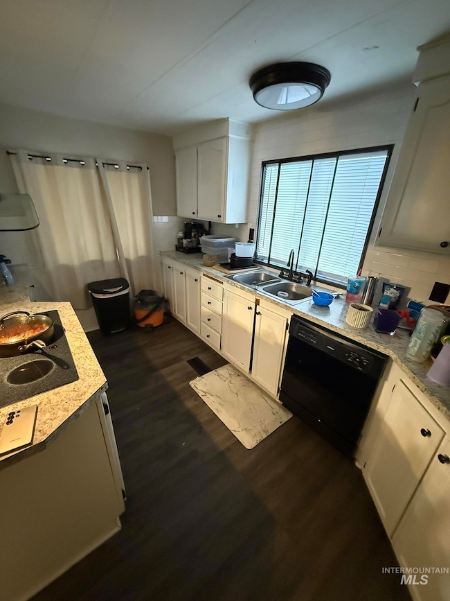 Kitchen with dark wood finished floors, dishwasher, white cabinetry, and stovetop