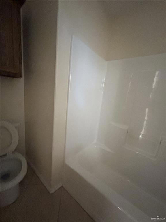 Bathroom with walk in shower, toilet, tile patterned floors, baseboards, and a tub to relax in