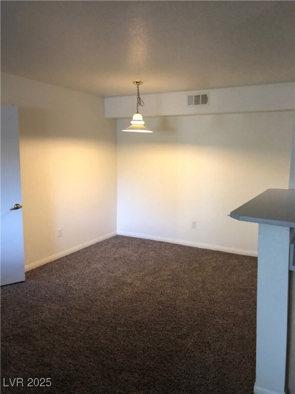 Unfurnished room with dark colored carpet and baseboards