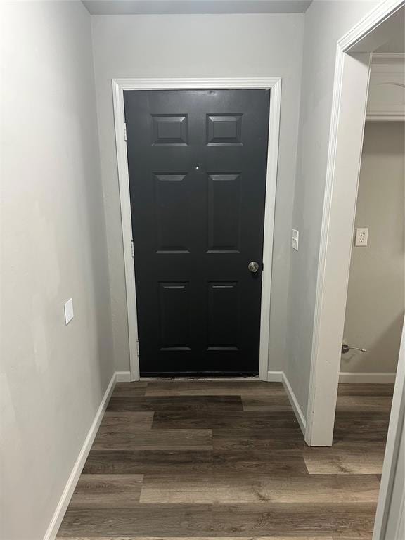 Doorway featuring baseboards and dark wood finishe