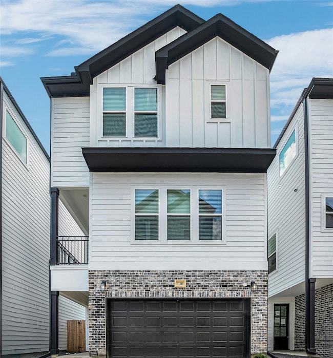 Modern three-story townhouses with a sleek design, featuring white siding, brick accents, and black garage doors. The complex has a clean, organized layout. Ideal for contemporary urban living.