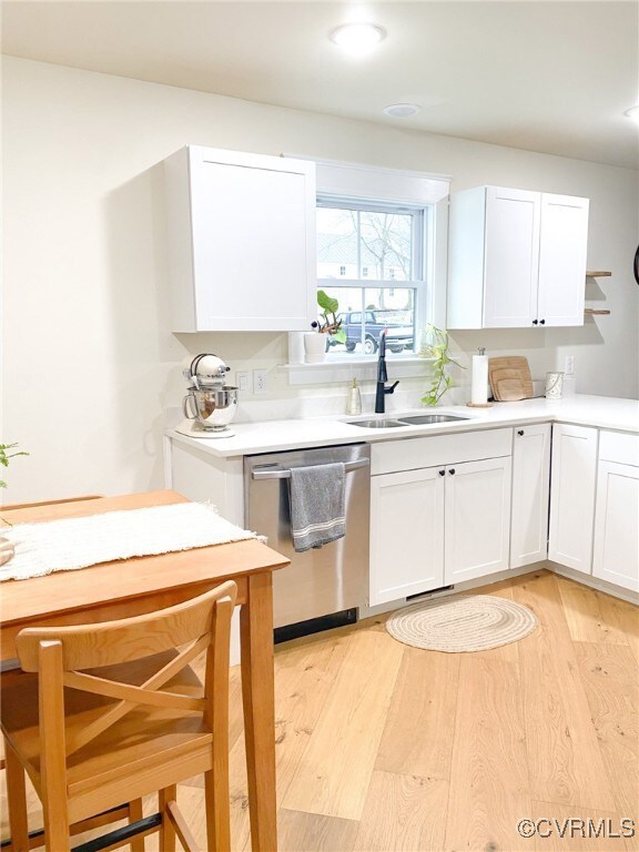 Kitchen with white cabinetry, dishwasher, light wo